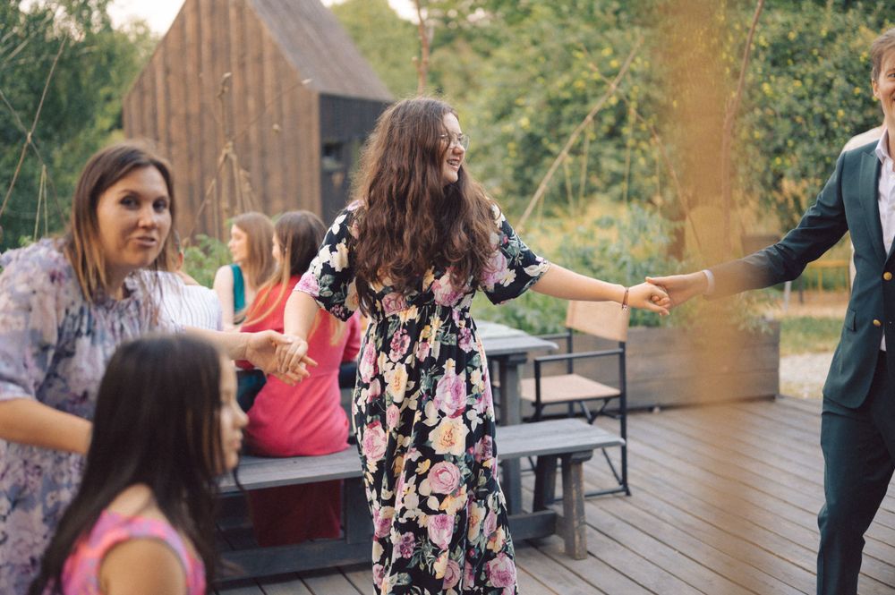 People dancing and celebrating on an outdoor wooden deck with a barn in the background.