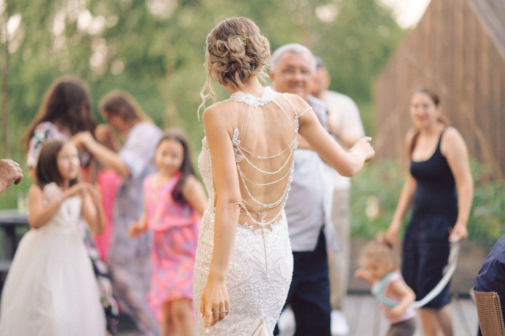 Back view of a detailed lace wedding dress at an outdoor celebration.