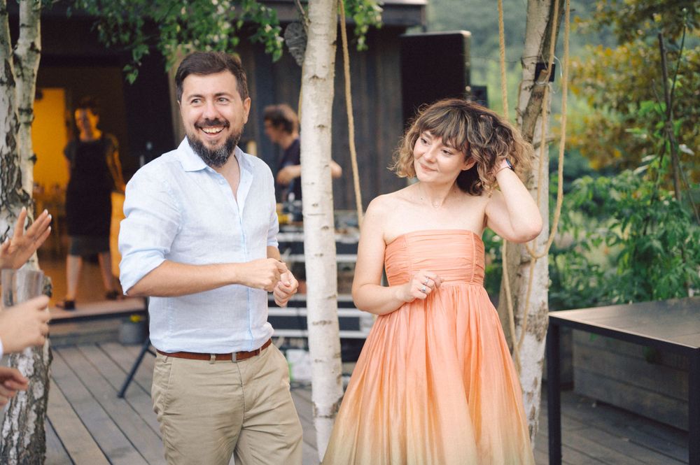 Couple enjoying a light moment at an outdoor party with peach-colored dress.