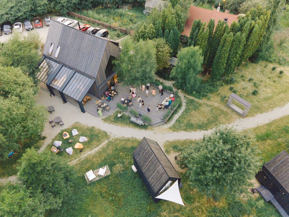 Aerial view of a rustic wooden barn venue with outdoor seating and paths surrounded by greenery.