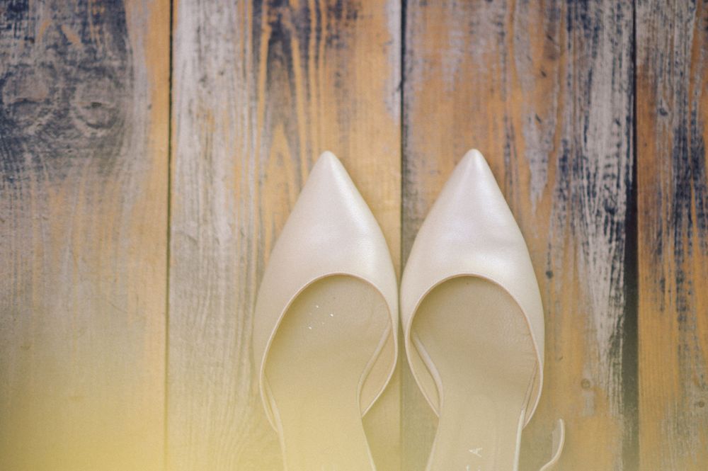 White bridal heels against a rustic wooden background.