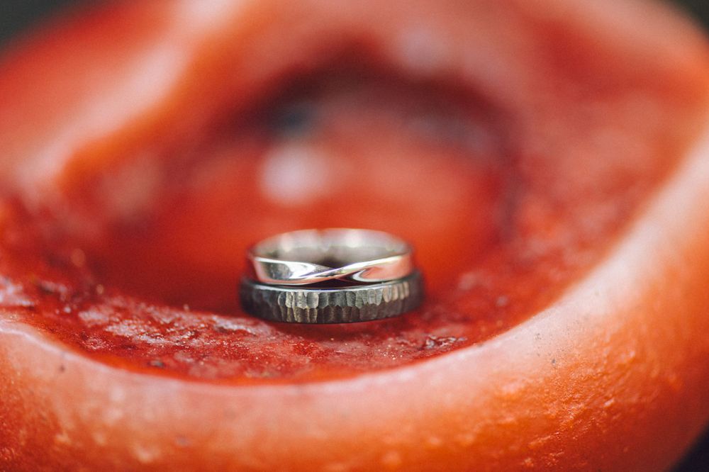 Wedding rings nestled inside a red flower macro shot.