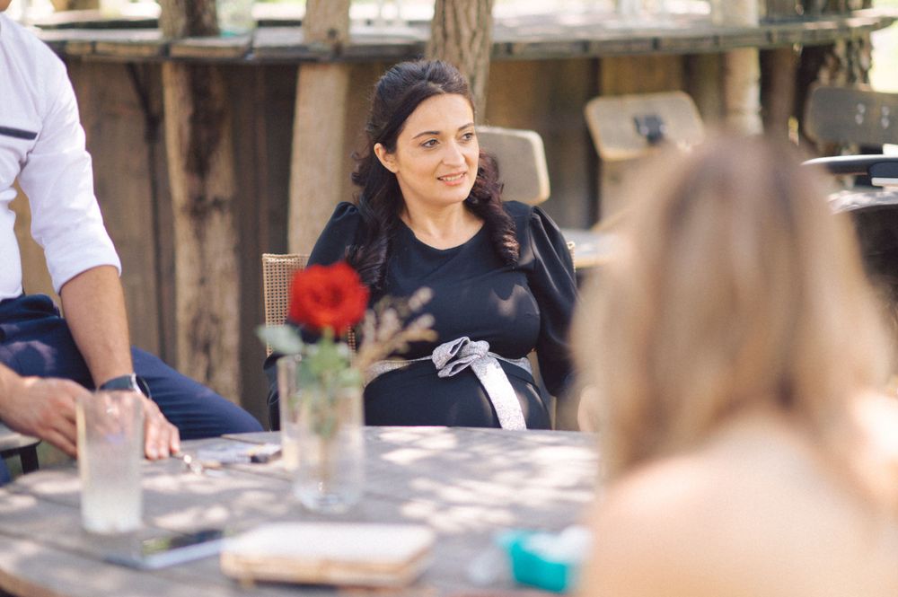 Wedding guests enjoying an outdoor dining setting with red flowers on the table.