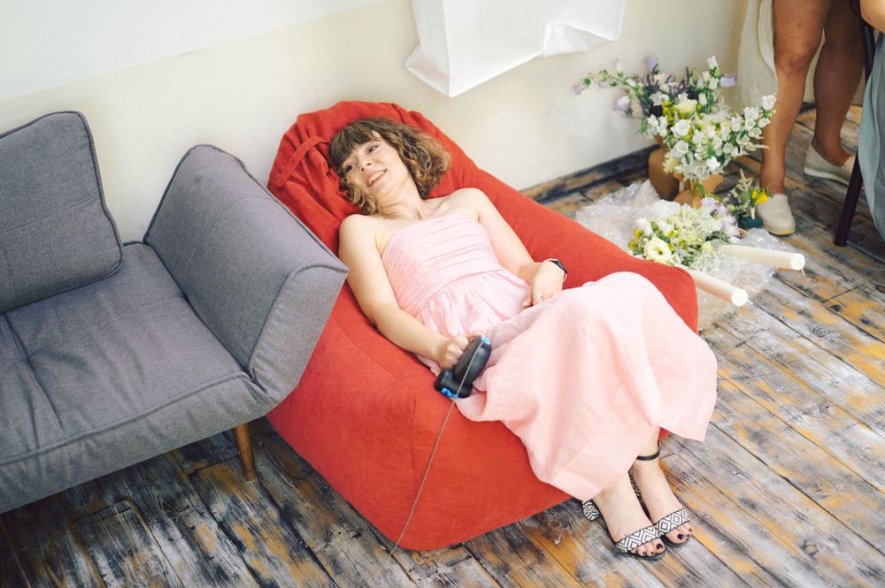 A person resting on a red bean bag chair wearing a pink dress.
