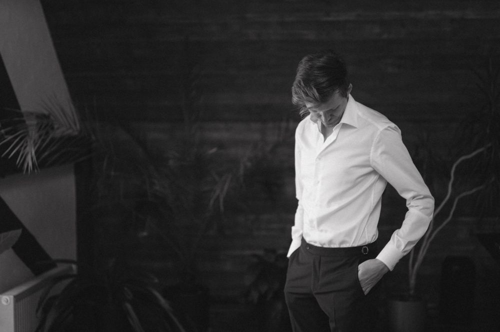 Black and white photo of someone in formal attire against a dark wooden wall.