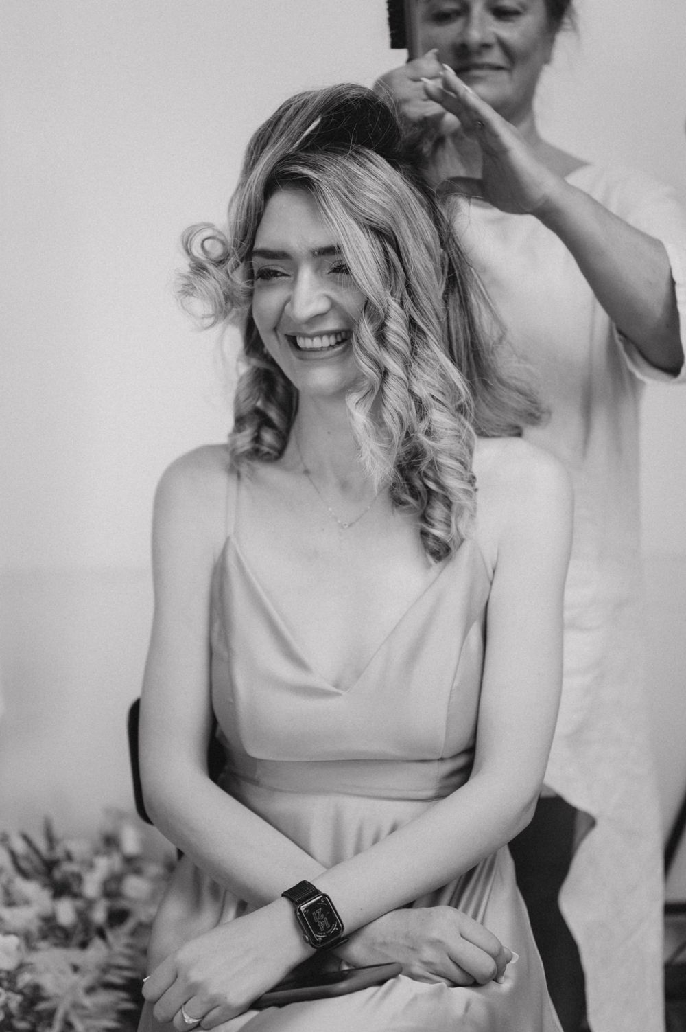 A joyful moment during hairstyling preparation in black and white.