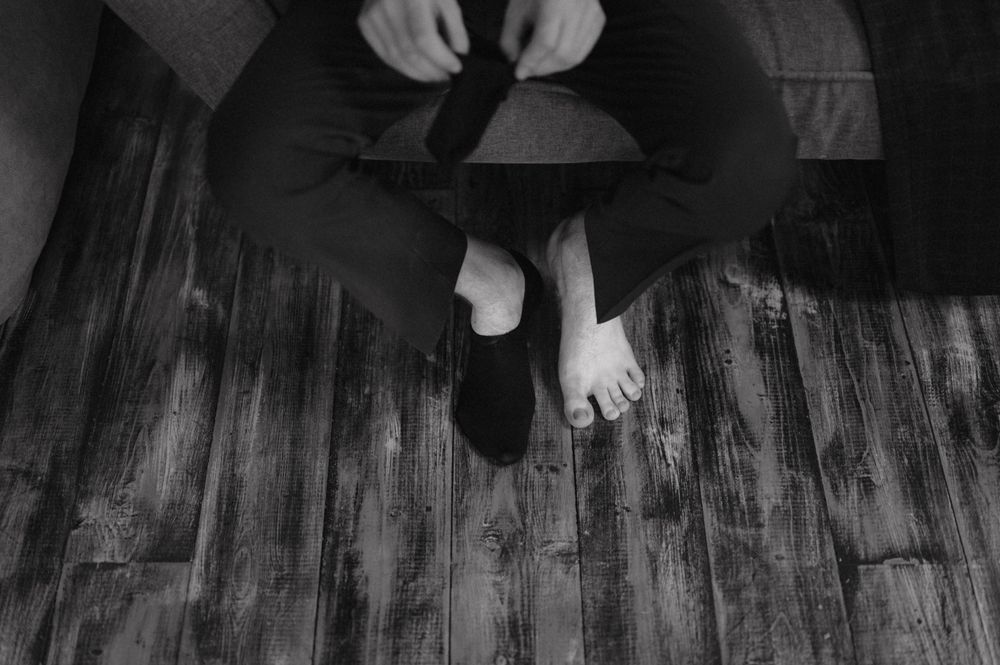 Artistic black and white overhead shot of feet against wooden flooring.