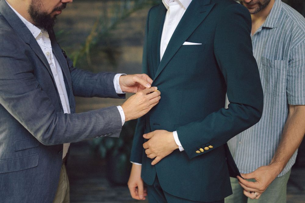 Close-up shot of people adjusting formal suit details and buttons.