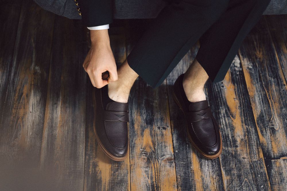 Close-up view of brown leather dress shoes on a dark wooden floor.