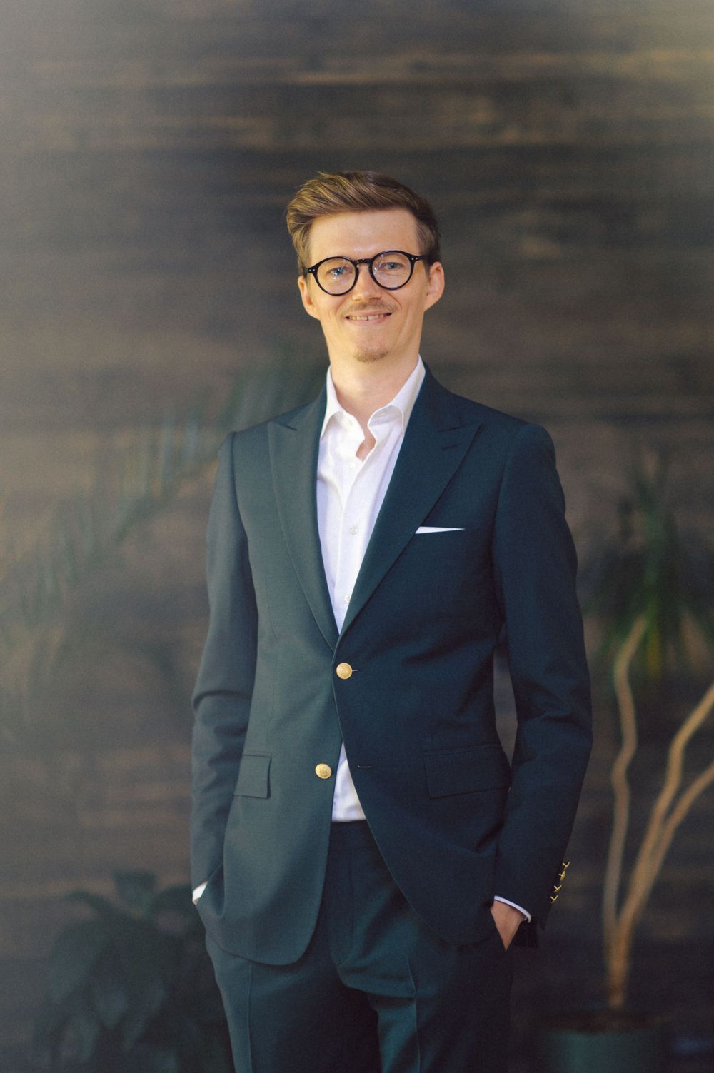 A navy blazer with gold buttons styled with a crisp white shirt against a dark wooden backdrop.