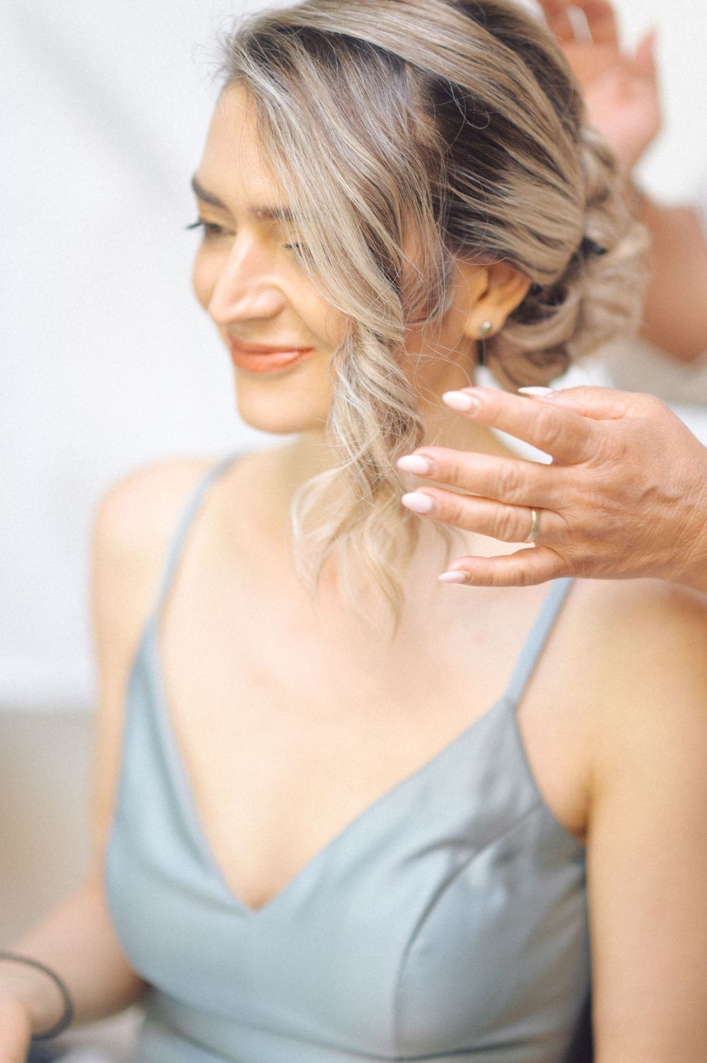 Beautiful hairstyling session showing gentle hands working on soft blonde waves.