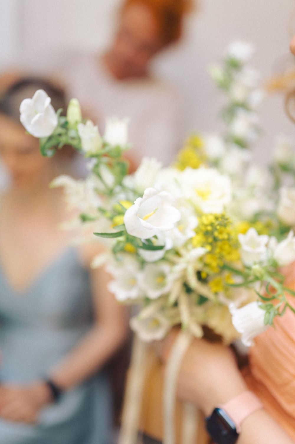 Delicate white and yellow floral arrangement with fresh greenery in soft focus.