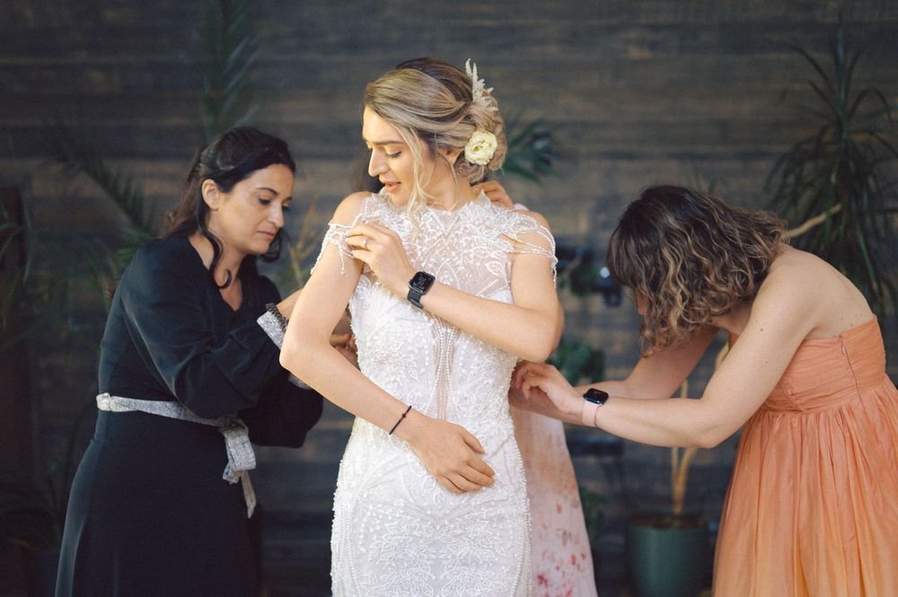 Final touches being made to a stunning white lace wedding dress during preparation.