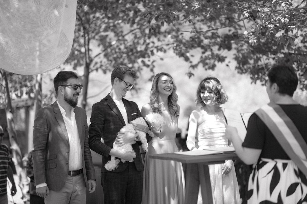 Black and white capture of outdoor ceremony gathering under trees.