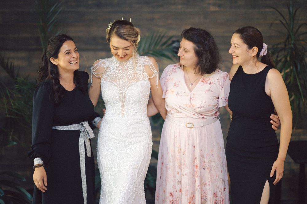 Bridesmaids in elegant black dresses surround a bride wearing a delicate white lace gown at a wedding celebration.
