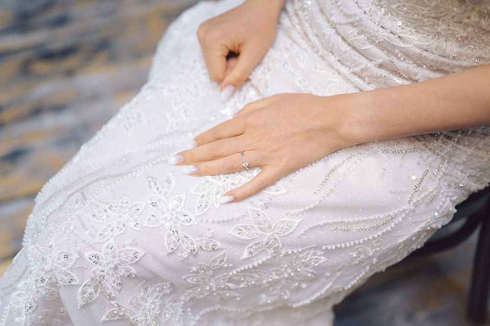 Close-up detail of intricate lace pattern on a white wedding dress.