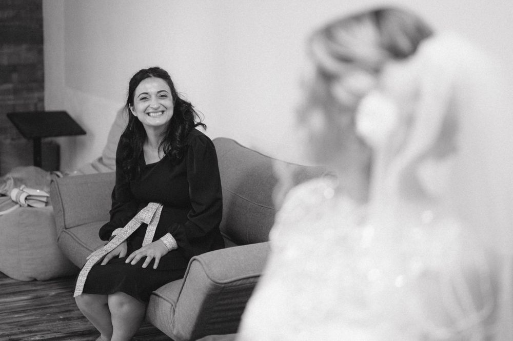 Candid black and white moment between wedding party members during preparation.