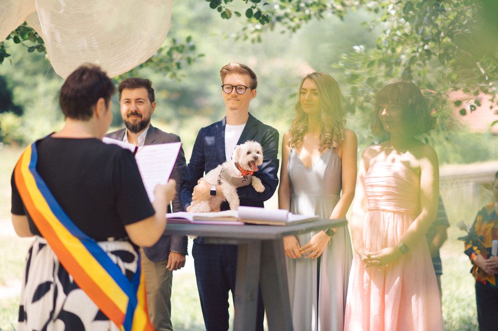 Intimate outdoor ceremony with white decorations and small dog in attendance.