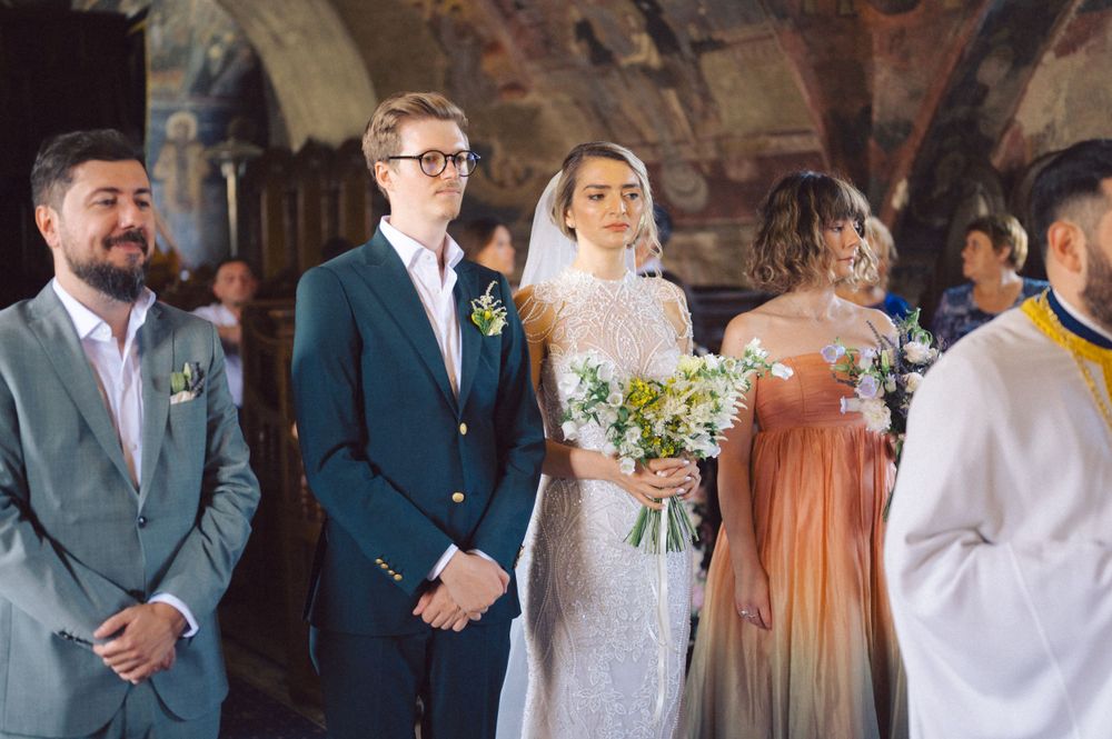Orthodox wedding ceremony taking place in a beautifully decorated church with painted walls.