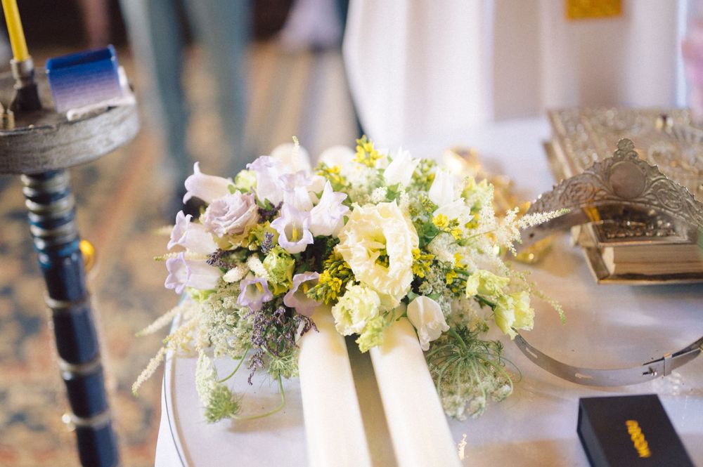 Delicate white and yellow floral wedding bouquet with ribbons on a decorated table.