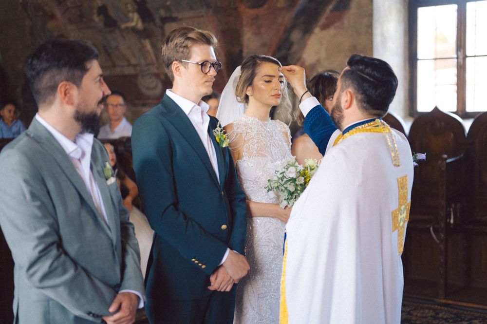 Orthodox priest conducts wedding ceremony in traditional vestments inside historic church.