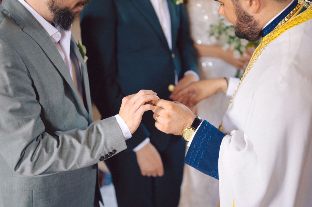 Close-up of hands exchanging rings during Orthodox wedding ceremony.