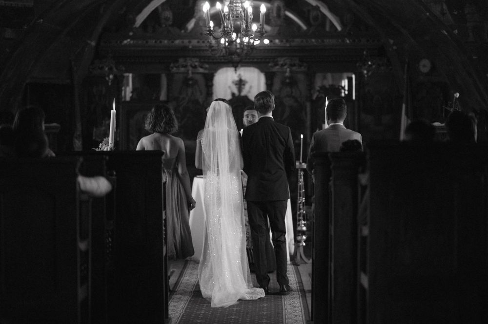 A romantic black and white wedding ceremony photo captured in a dimly lit church.