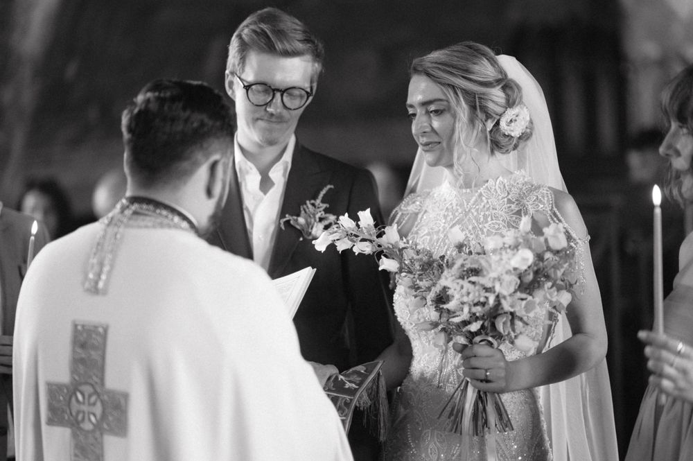 An Orthodox wedding ceremony takes place with the priest performing traditional rites.