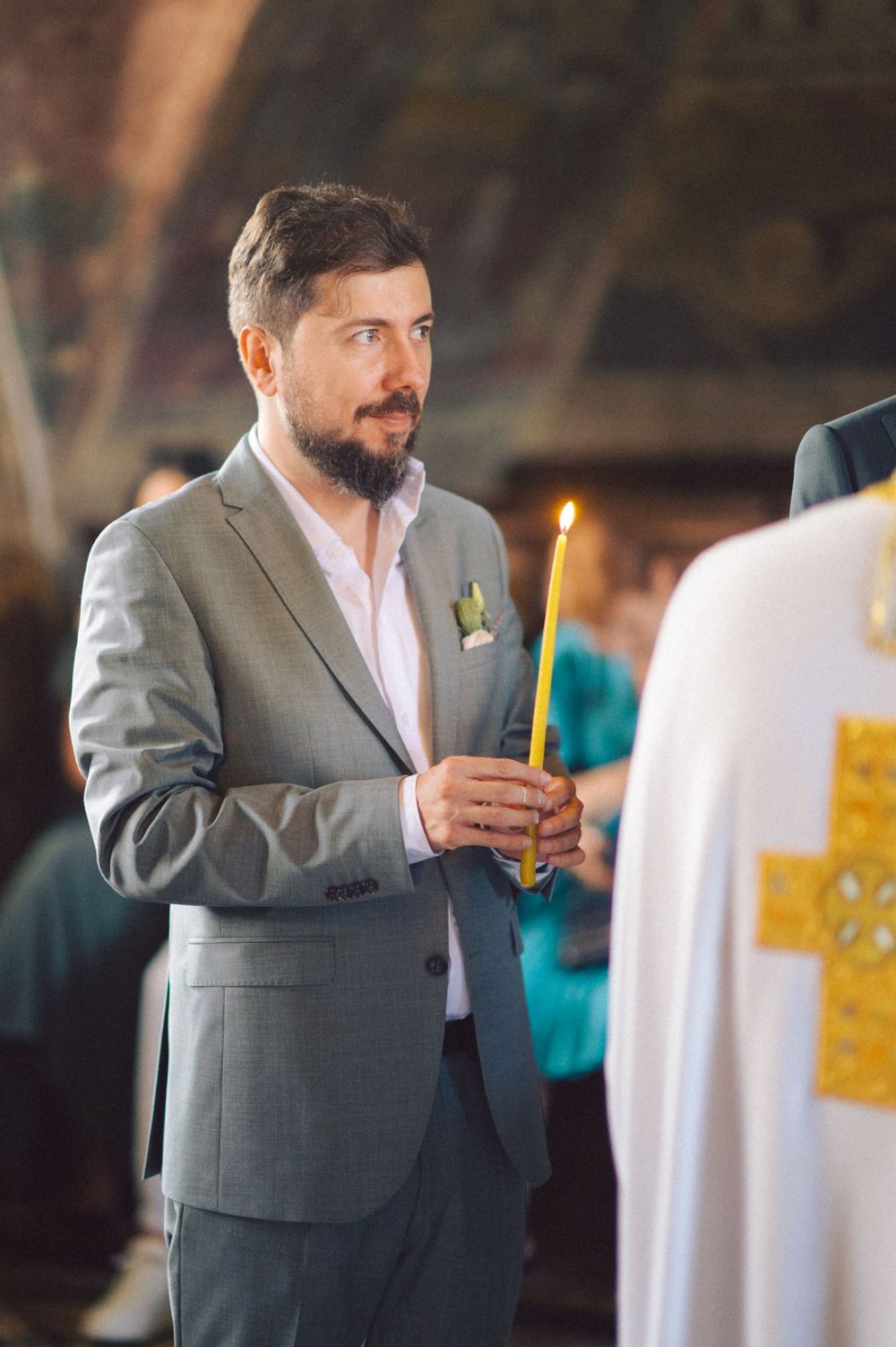 A participant holds a lit candle during an Orthodox church ceremony.