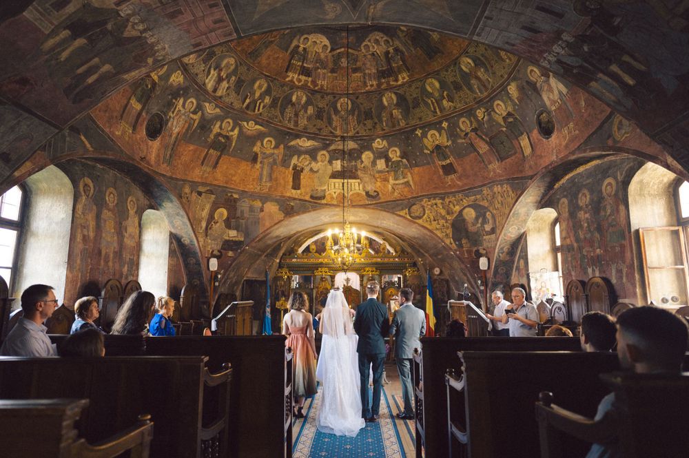 Elegant church wedding ceremony in a historic chapel with ornate frescoed dome ceiling and arched windows.