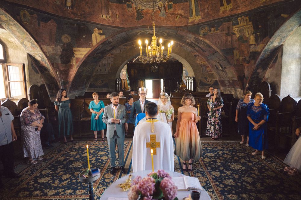 Traditional religious ceremony in a historic church with decorated walls and chandelier.