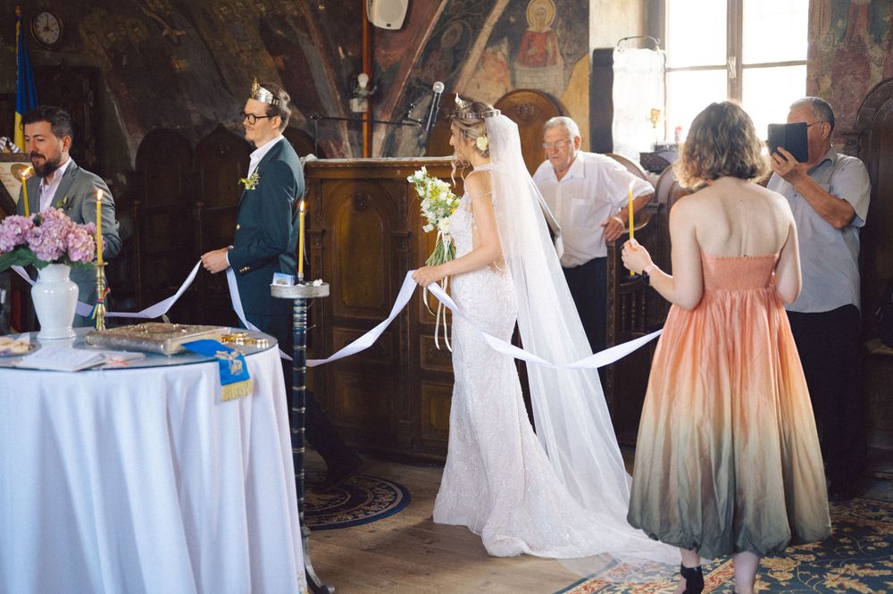 Wedding reception gathering in an ornate church hall with decorative walls and round tables.