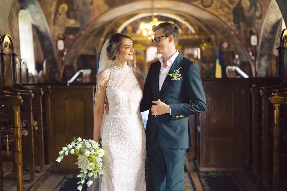 Romantic wedding portrait in historic church with painted frescoes and wooden pews.
