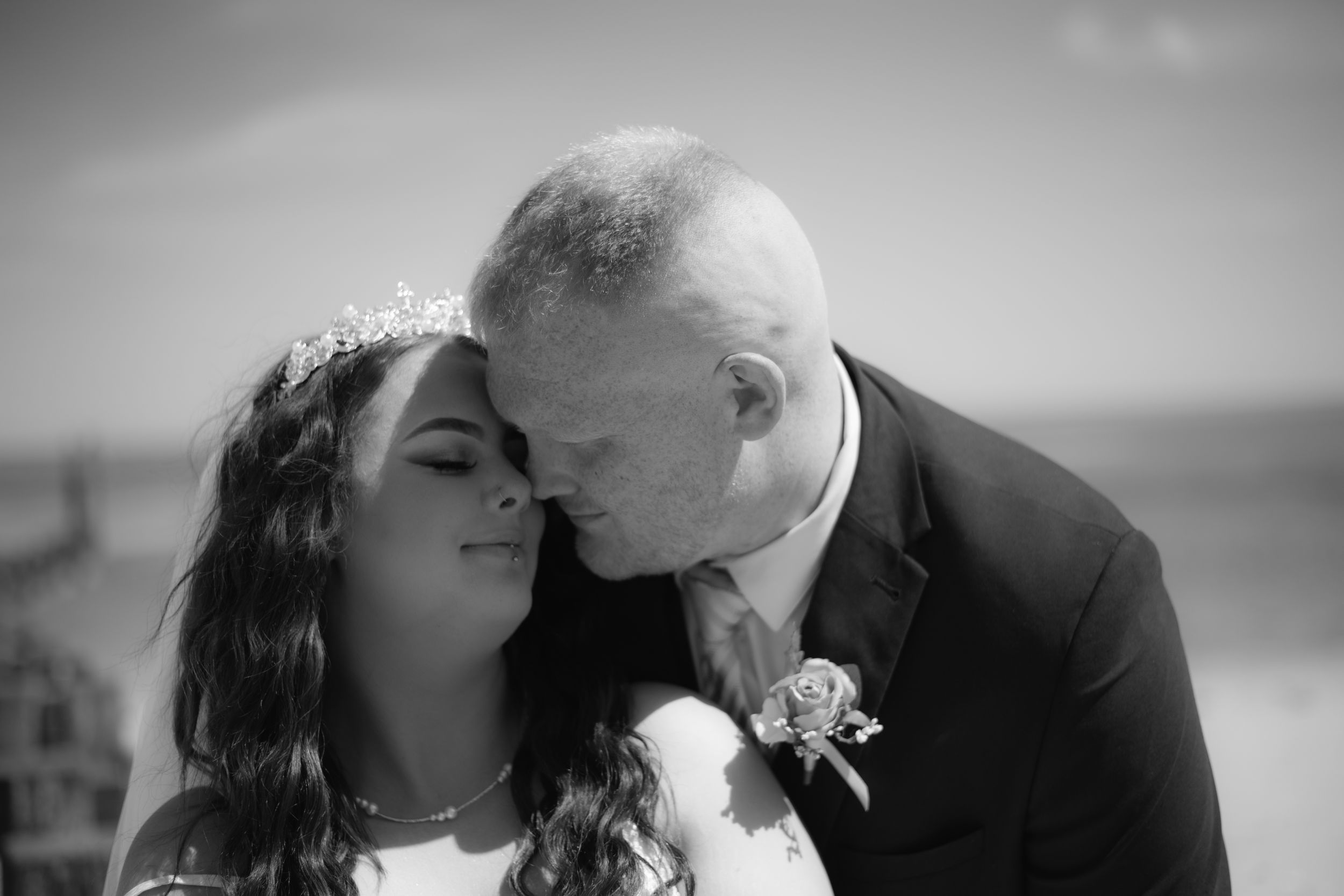 Intimate black and white portrait of newlyweds sharing a romantic moment by the ocean.