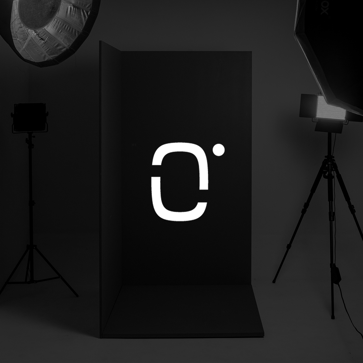 Professional photography studio setup with lighting equipment and a black backdrop displaying a white logo.
