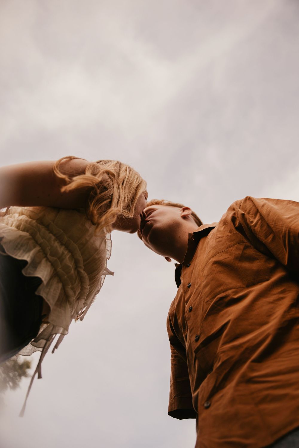 A dramatic low angle view of two people in contrasting white and brown clothing against an overcast sky.