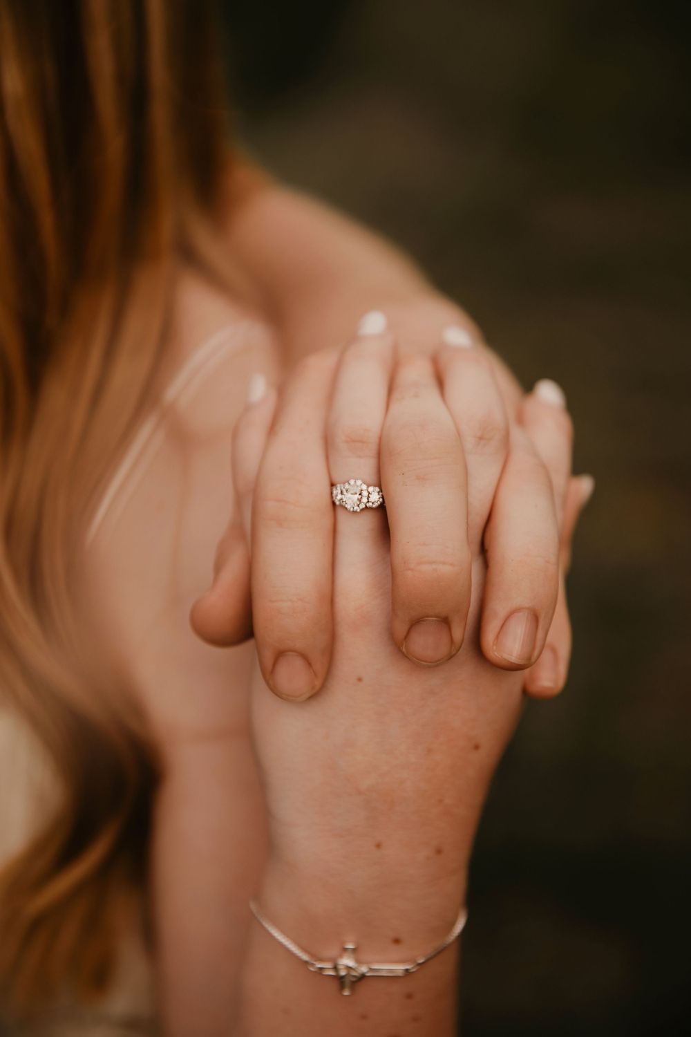 Close-up view of hands showing an engagement ring with simple thin silver bands and a small diamond solitaire.