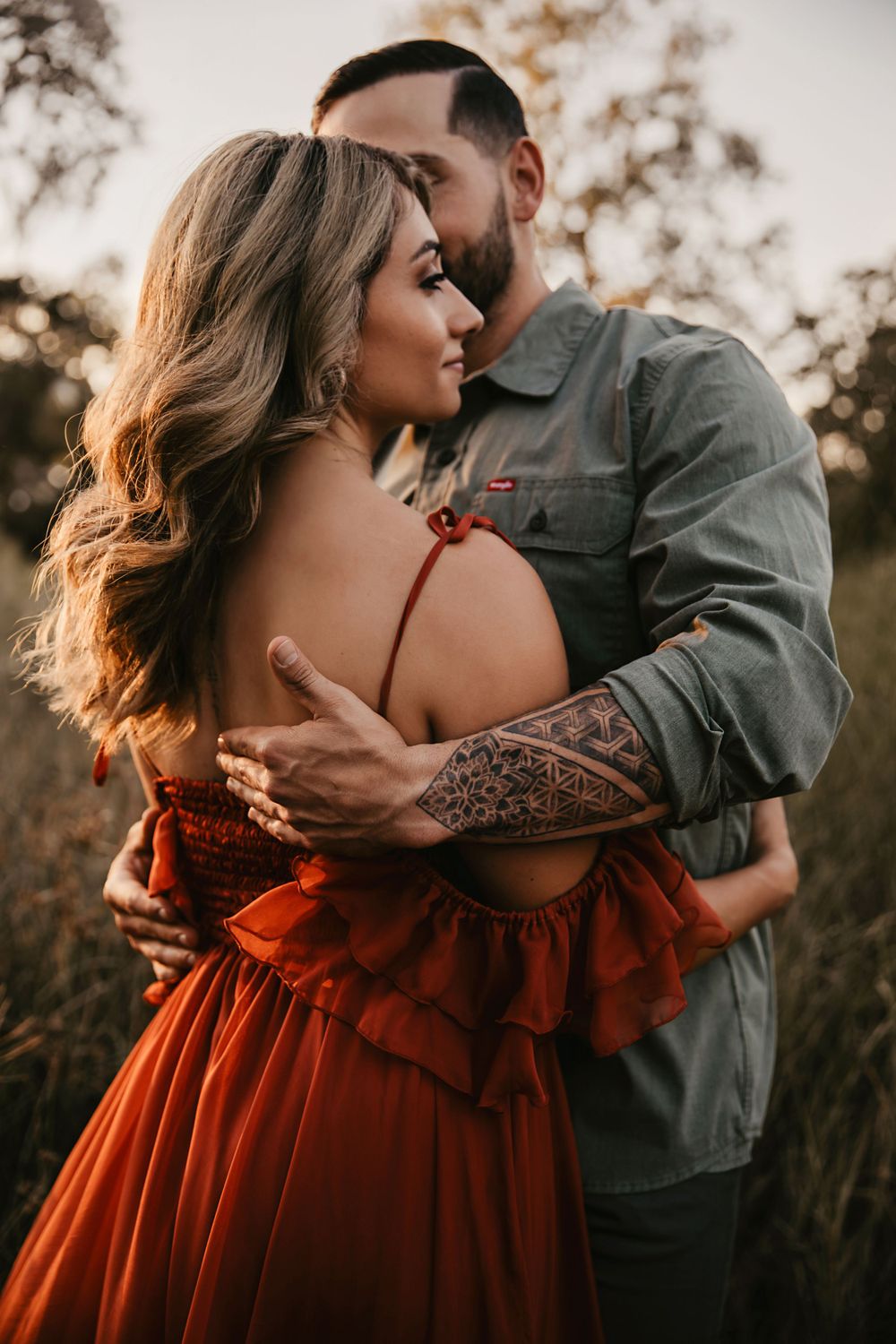 Intimate couple portrait with woman in red dress during golden hour.