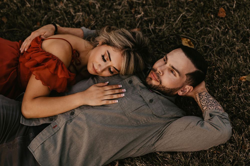 Loving couple lying in grass during sunset photoshoot.