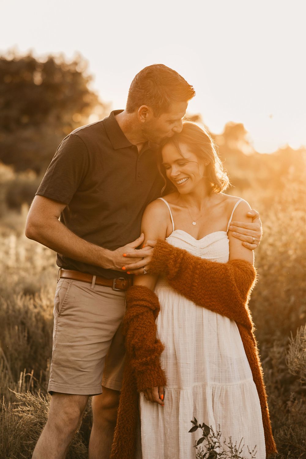 Loving couple embracing in golden hour sunlight against natural outdoor background.