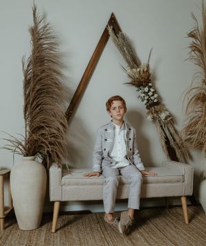 Niño en su sesión de comunión en Valencia, sonriendo con luz natural en un decorado boho.