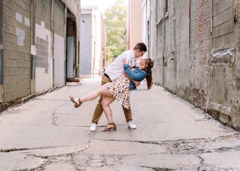 A romantic dance dip pose between two people in a urban alleyway.