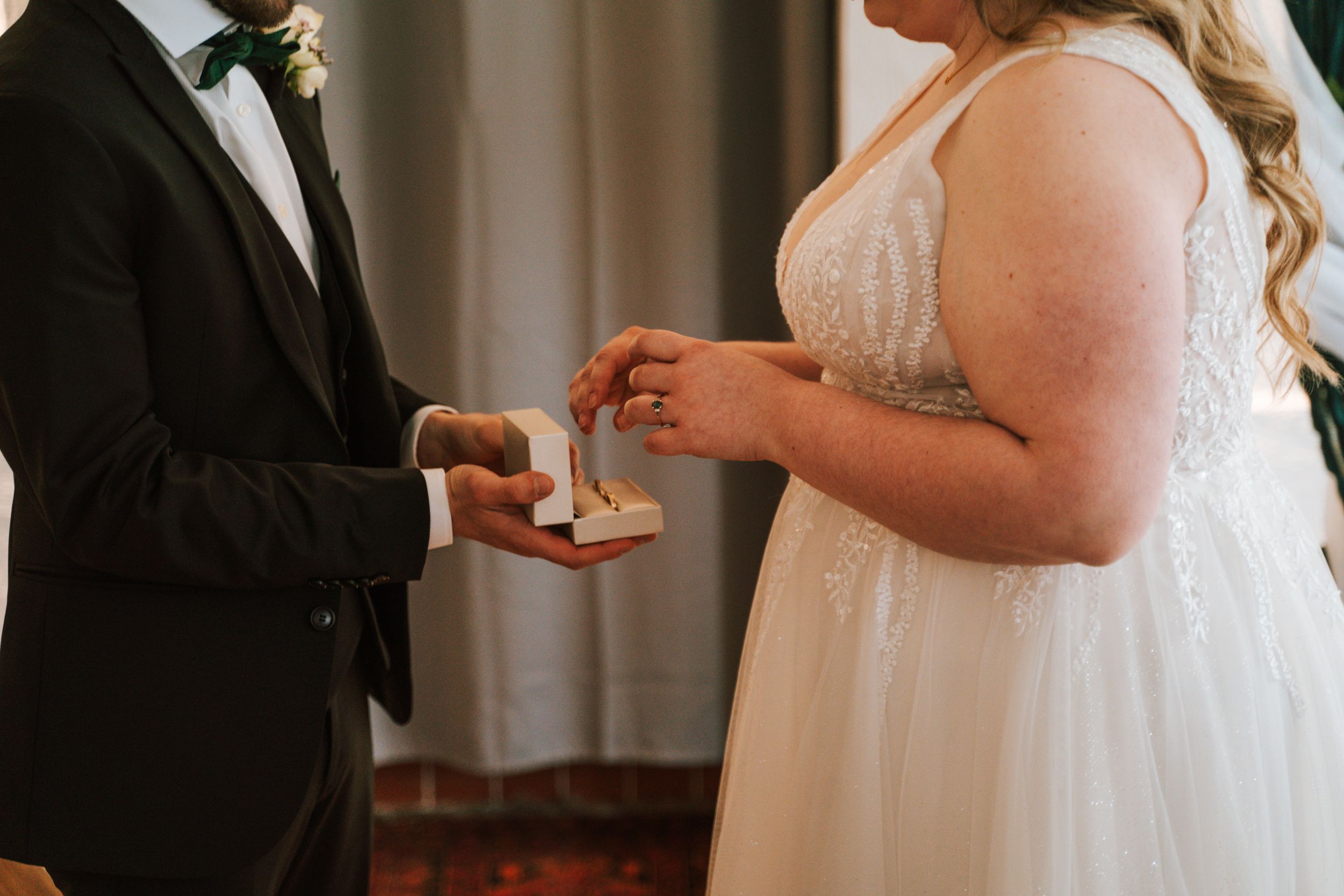 Close-up of wedding ring exchange between bride and groom during ceremony.