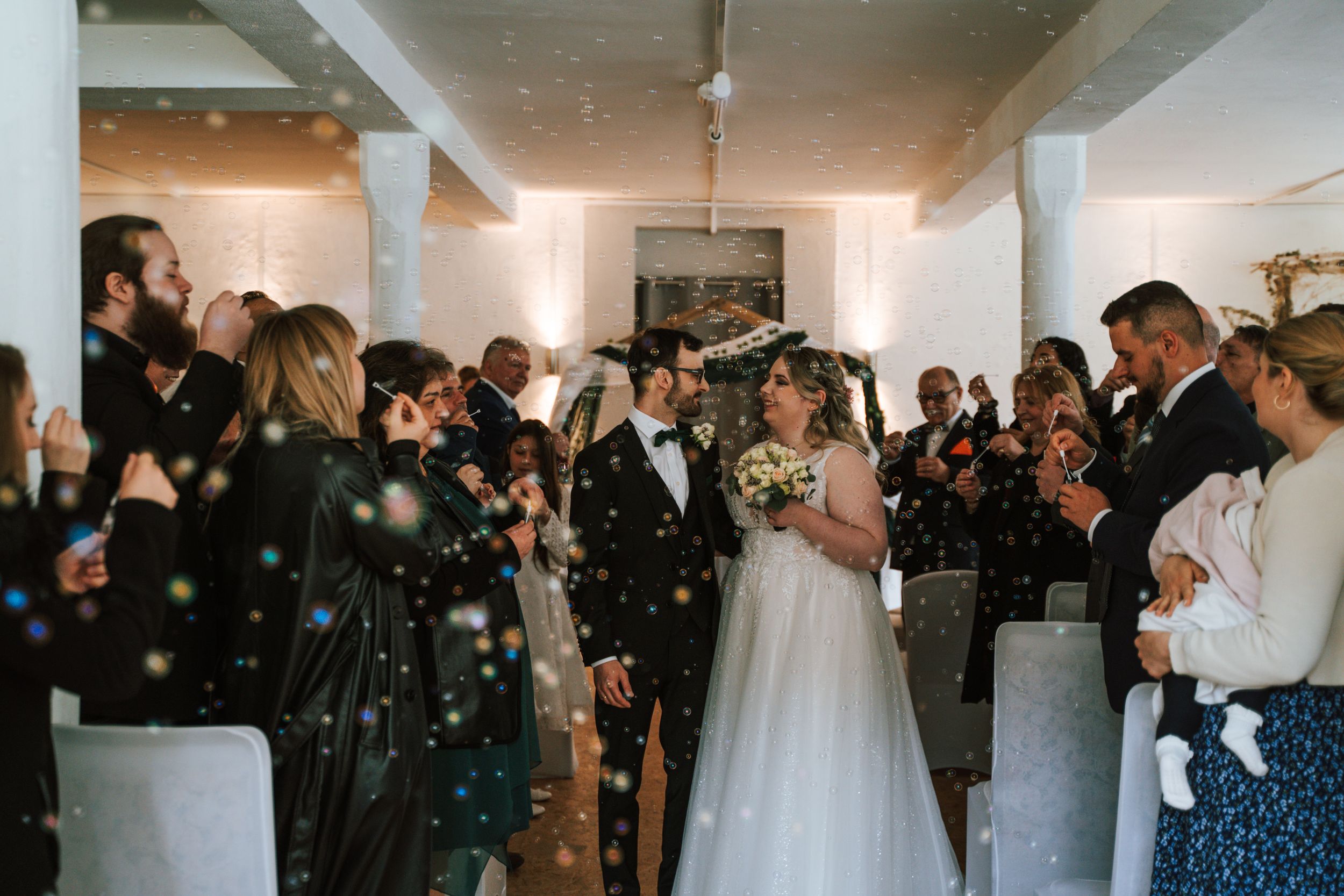 Wedding guests celebrate and applaud during indoor reception.