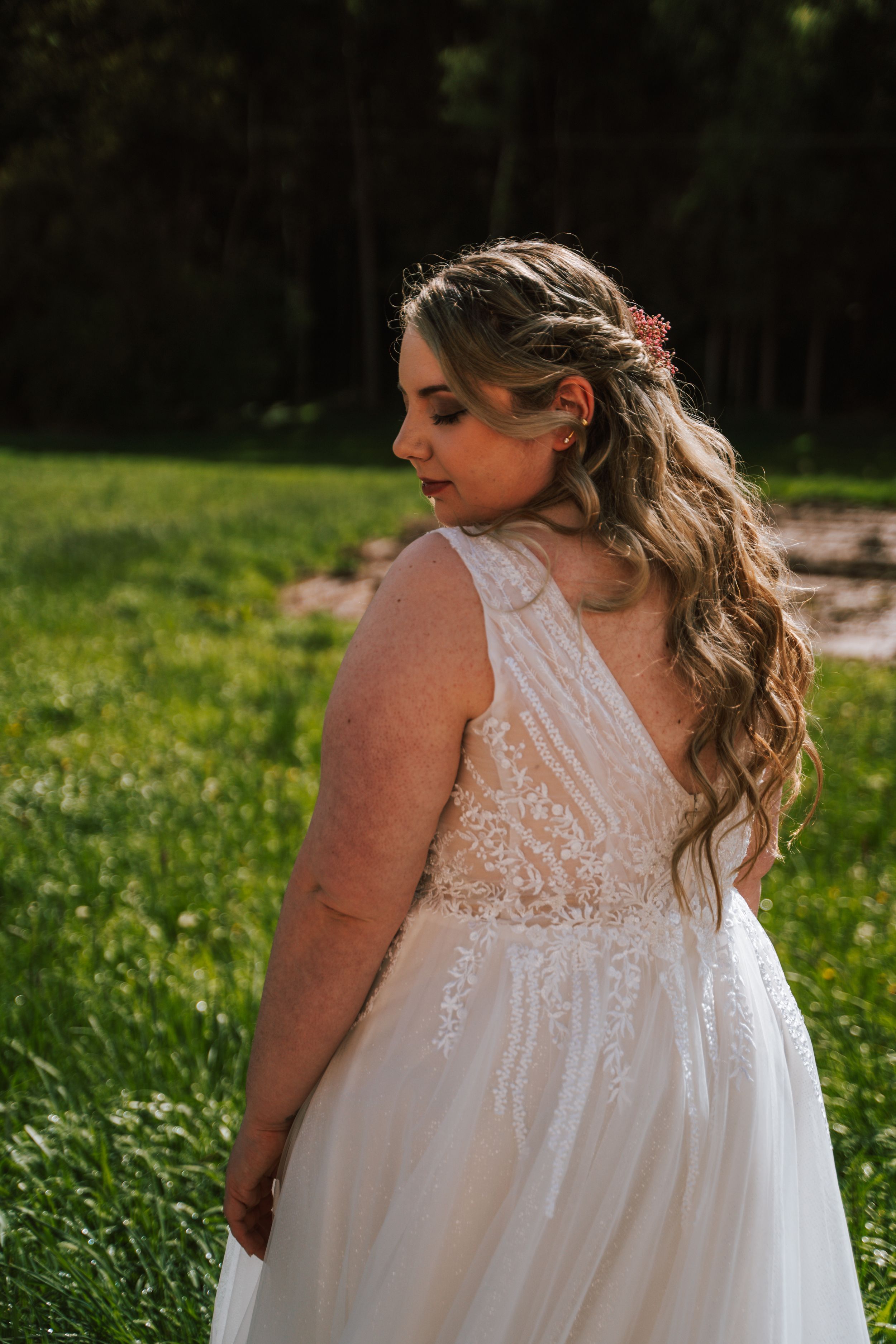 Detailed back view of lace wedding dress in outdoor setting.