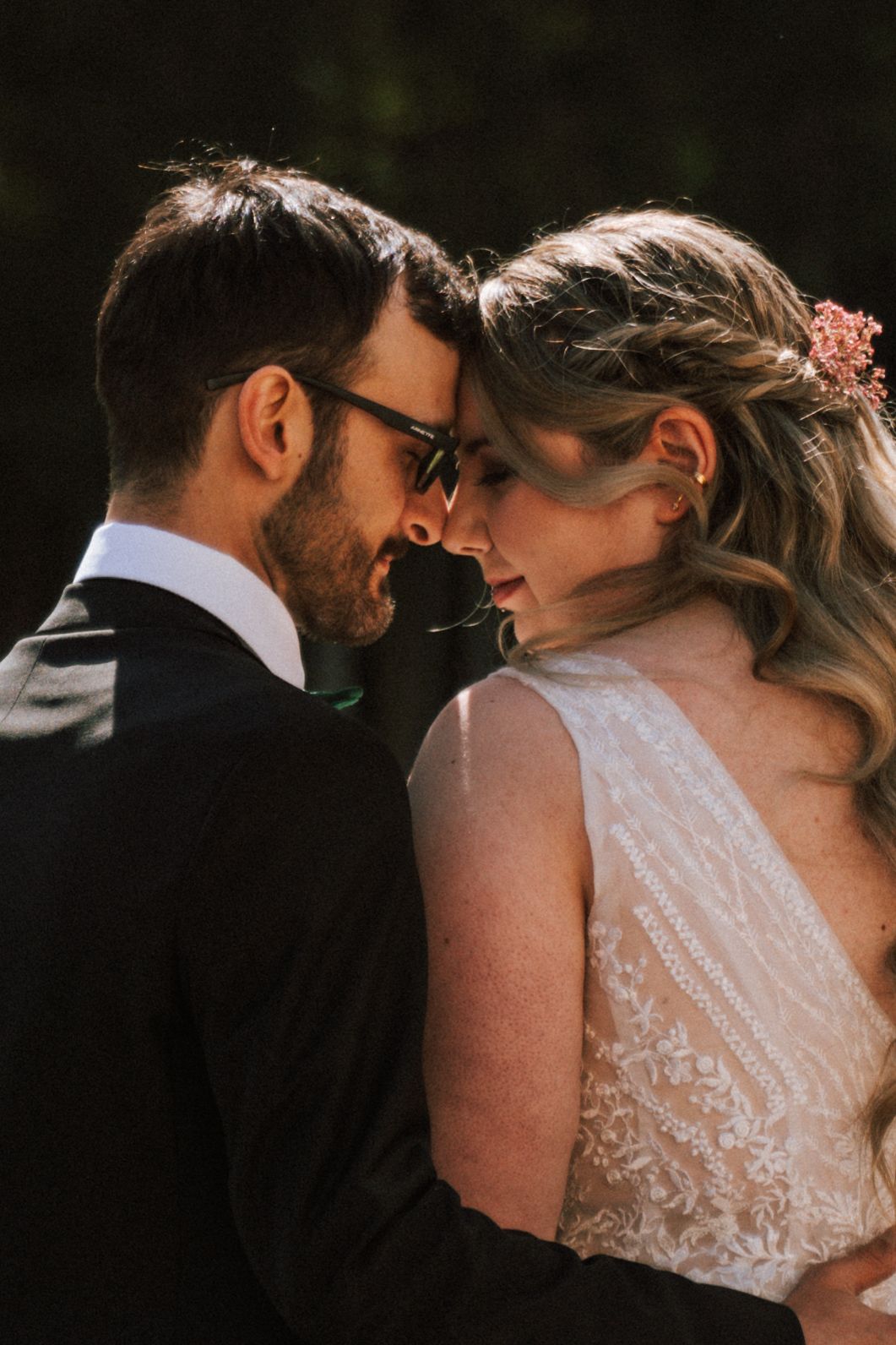 Intimate close-up of newlyweds sharing a tender moment against natural backdrop.