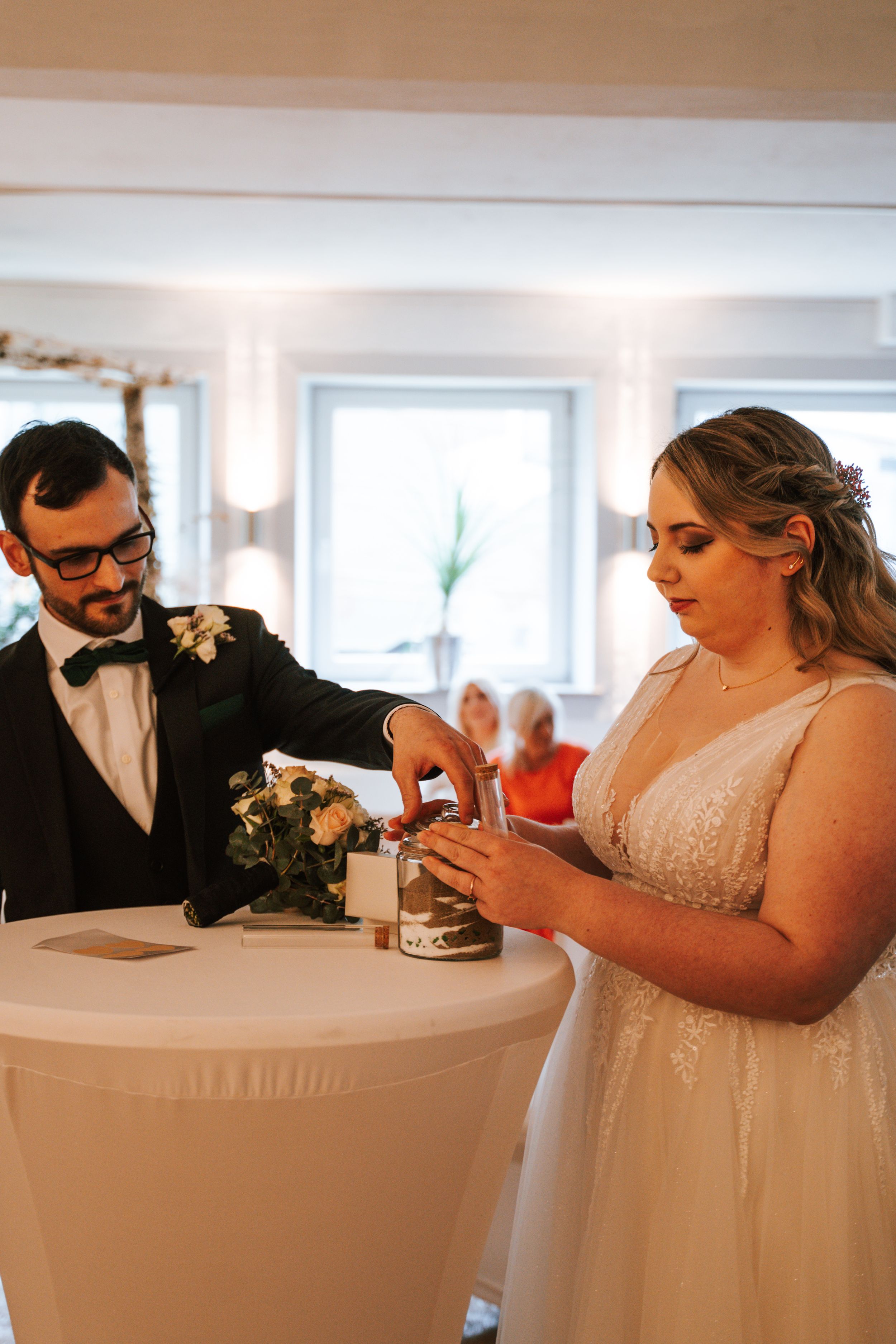 Newlyweds sharing intimate moments while seated in white chairs at their reception.