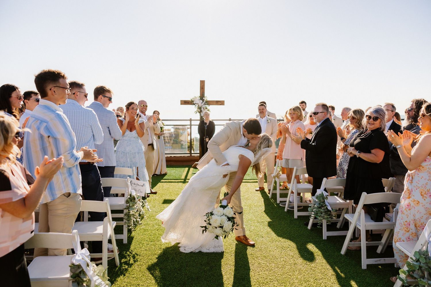Bride and groom share a joyful moment walking down the aisle at an outdoor wedding ceremony.