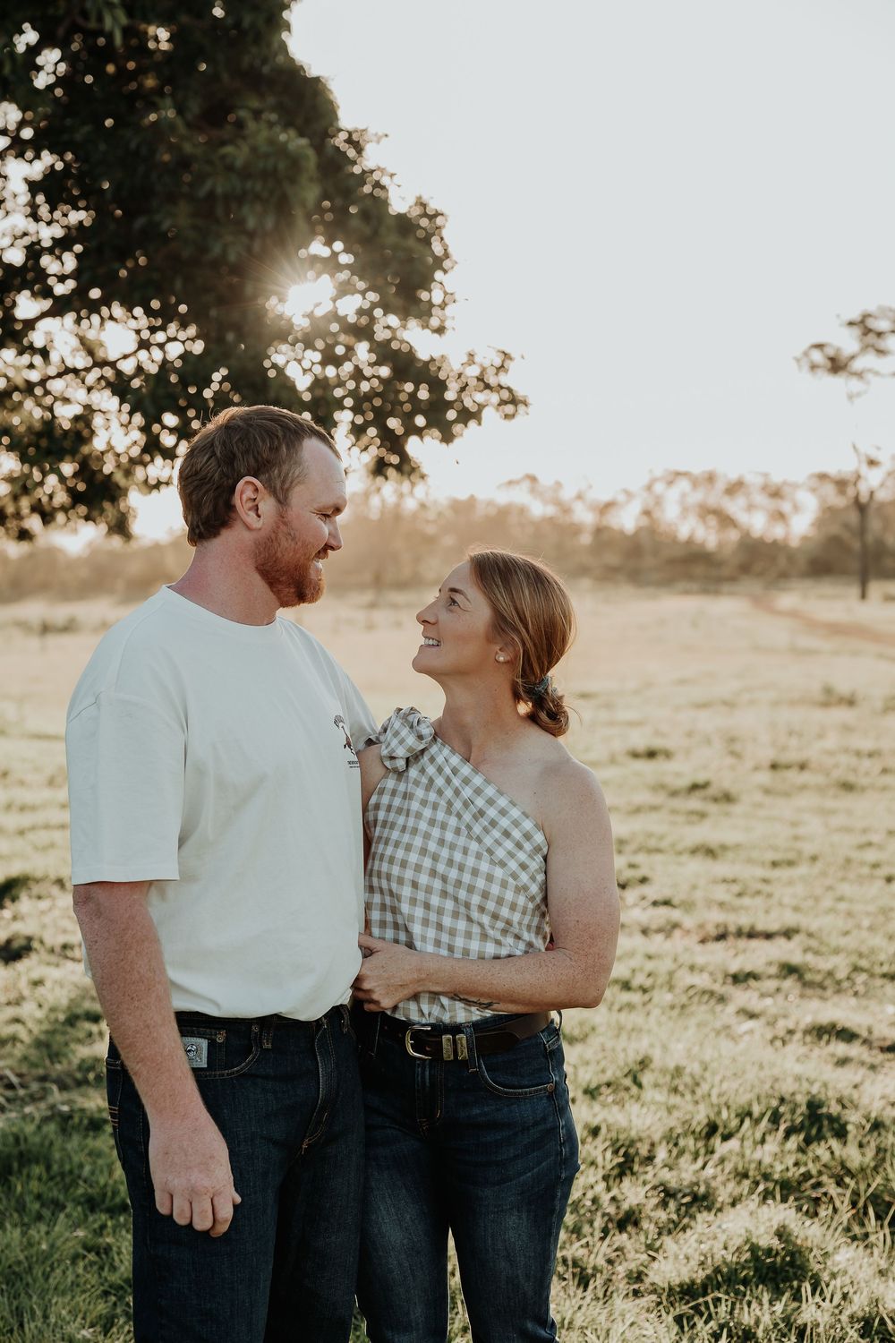 Couple in casual attire sharing tender moments in a sunlit bororen field.