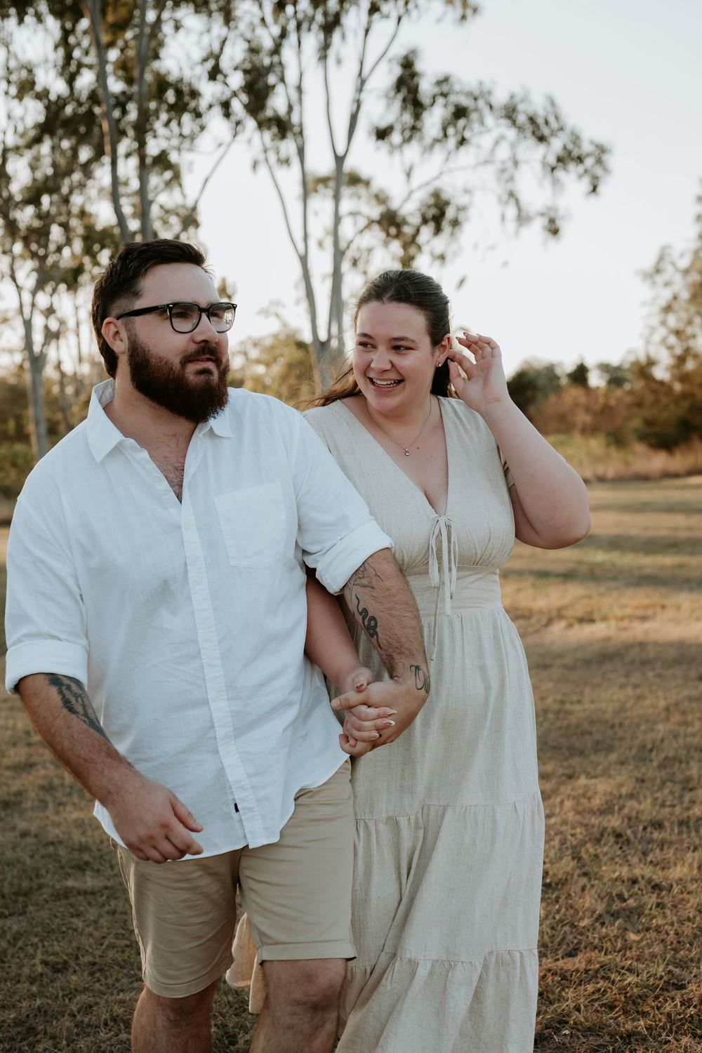 Couple in light summer attire laughing together in a sunny calliope outdoor setting.